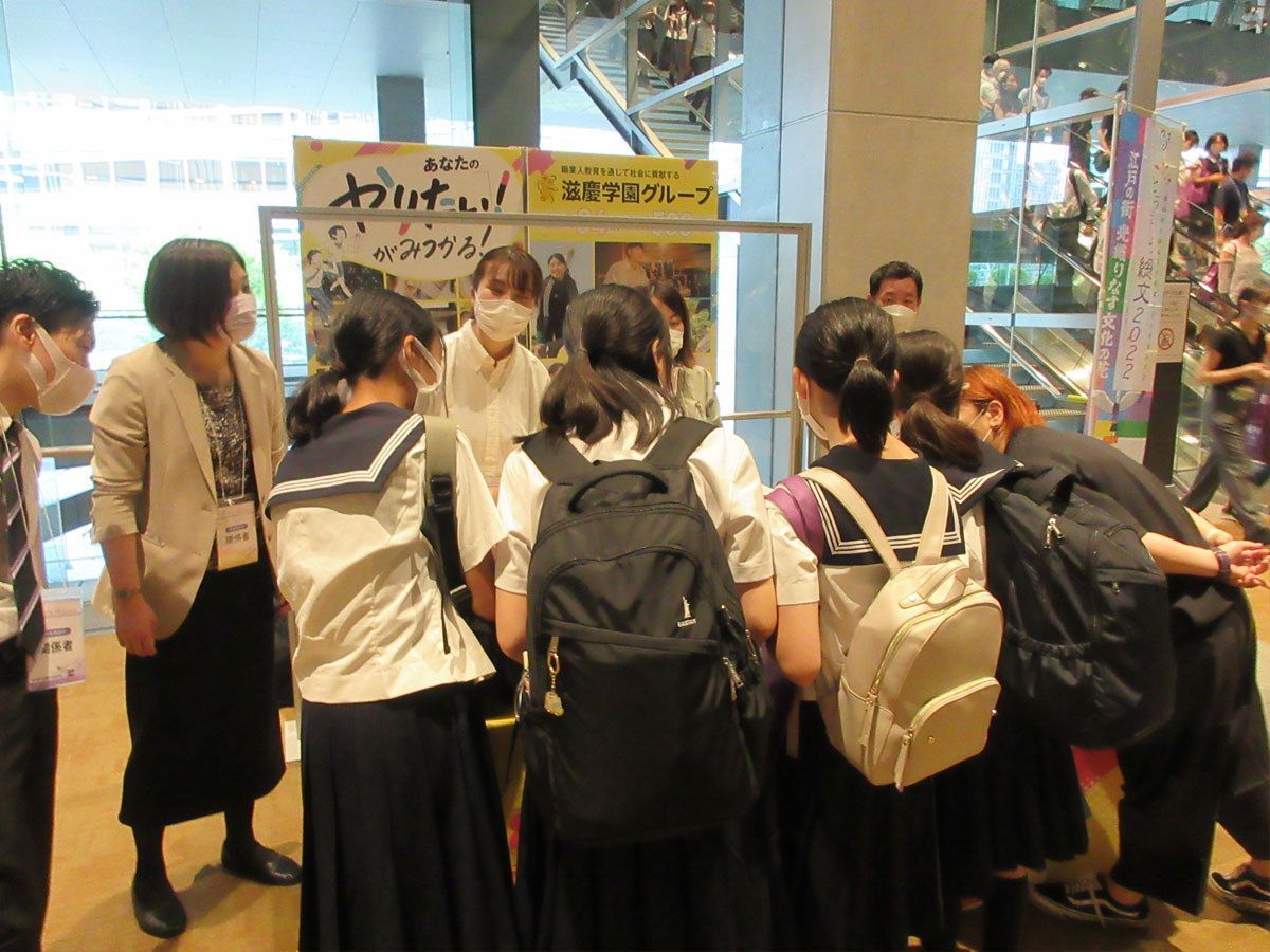 総合開会式会場の東京国際フォーラムのロビー、本学園のブースを訪れた高校生に笑顔で対応しました