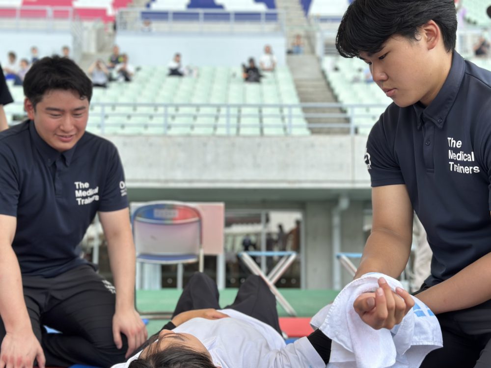 選手の引き手のケアを入念に行う学生トレーナー